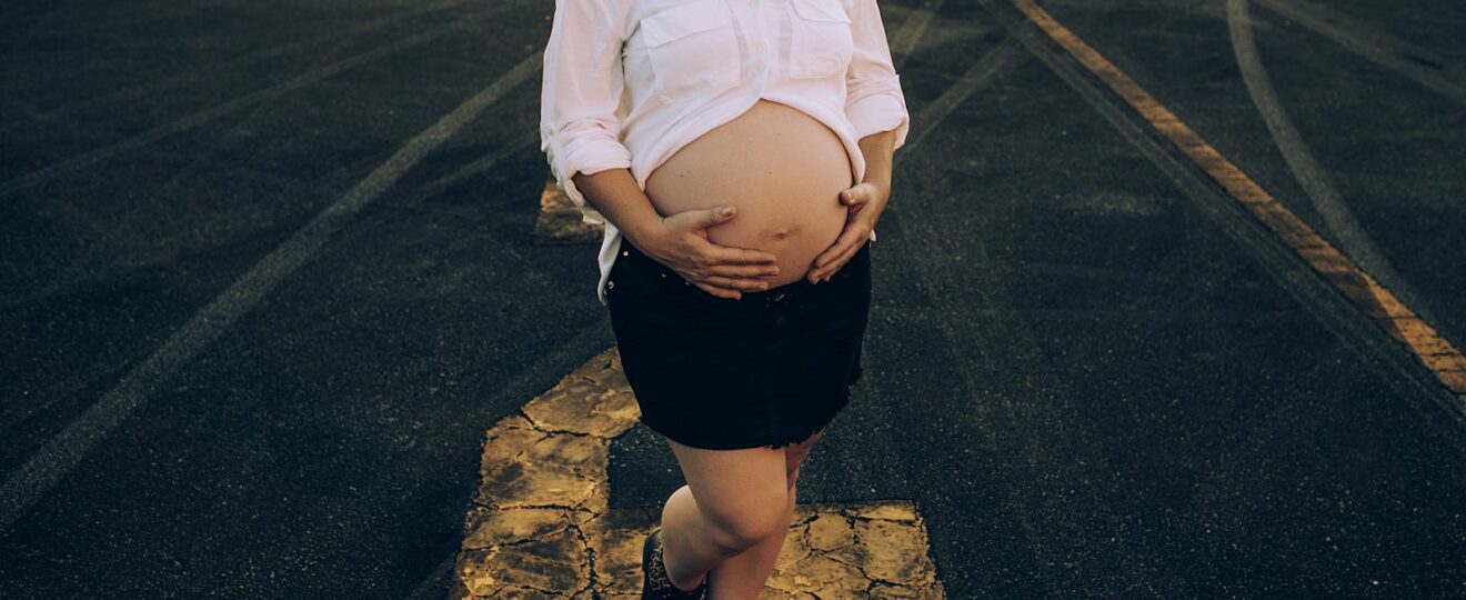 woman in white dress shirt and black skirt standing on gray asphalt road during daytime