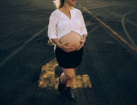 woman in white dress shirt and black skirt standing on gray asphalt road during daytime